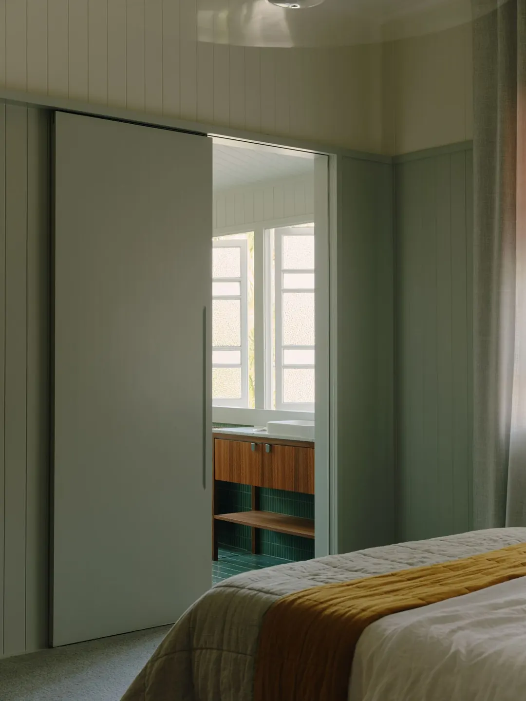Main bedroom with a quilted coverlet, a mustard throw and a sliding door