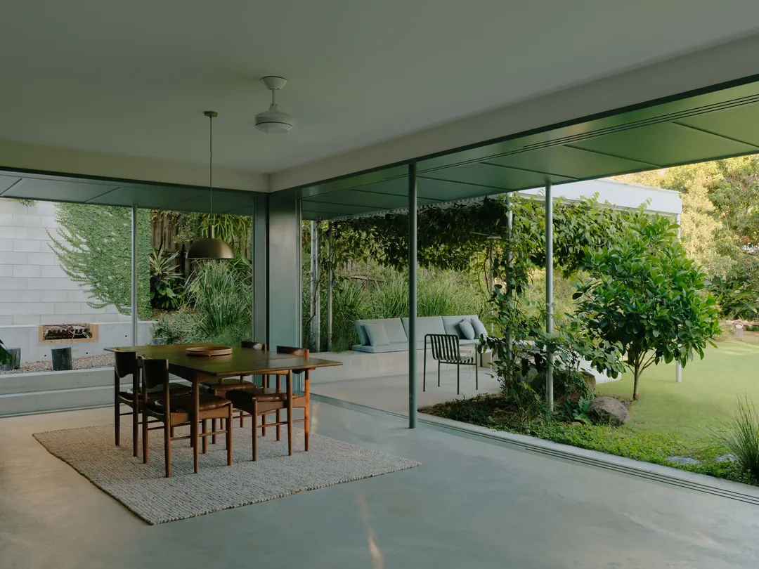 The mid-century living and dining room under the house, glass doors open to the garden
